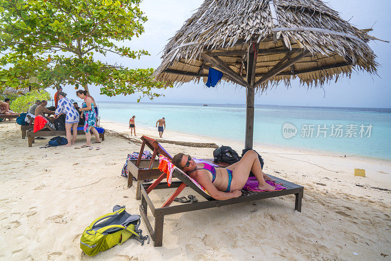 在马来西亚婆罗洲的热带岛屿Pom Pom上，美丽的女人躺在沙滩椅上，享受着碧绿的海水